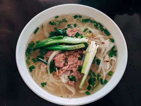 Bowl of pho with sliced beef, rice noodles and spring onion