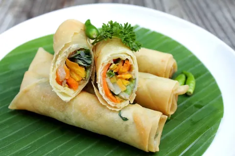 Spring rolls filled with carrot and cabbage on a banana leaf