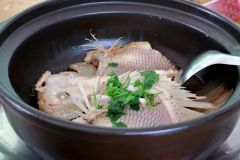 Whole steamed fish in a claypot with coriander and shallot