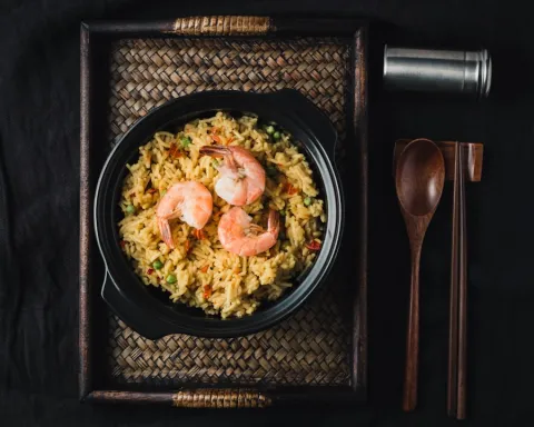 Fried rice topped with prawns in a black bowl