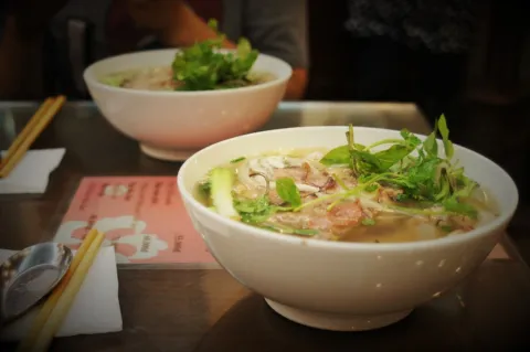Bowls of clear-broth chicken noodle soup on a table